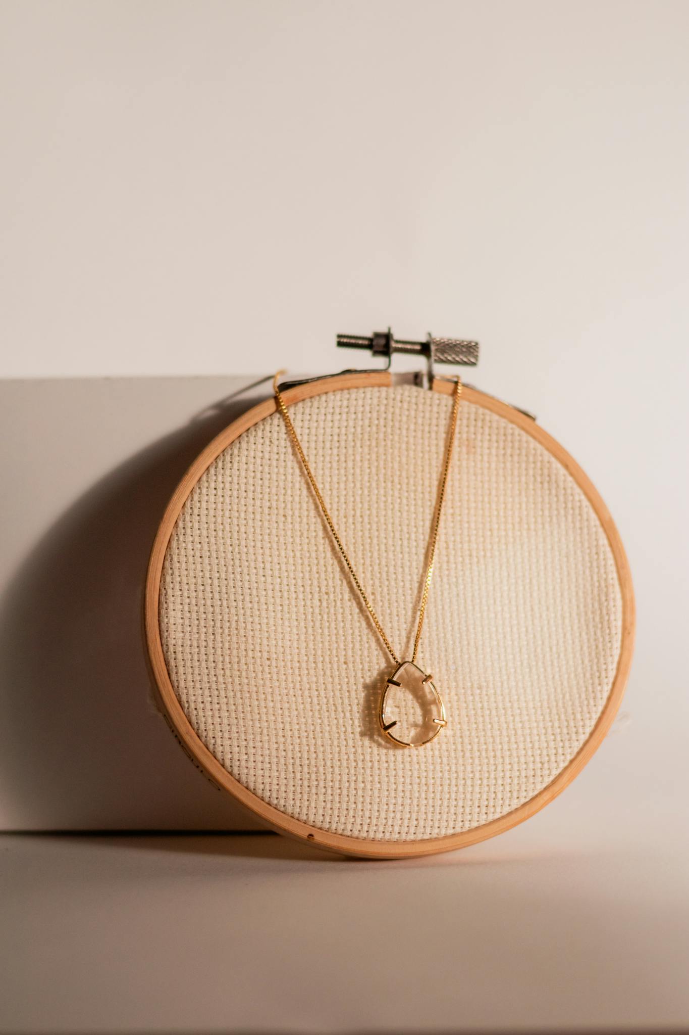 A beautifully crafted handmade crystal necklace elegantly hung on a wooden hoop, showcasing simplicity and style.