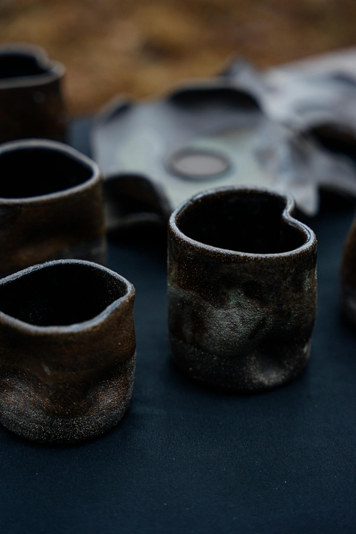Close-up of rustic handmade ceramic mugs showcasing unique textures and earthy tones.